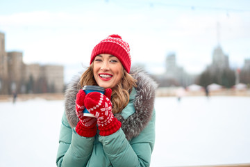 Beautiful lovely middle-aged girl with curly hair warm winter jackets stands ice rink background Town Square.