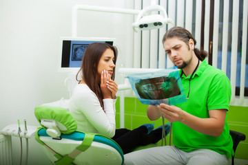 Dentist in dental office talking with female patient and preparing for treatment