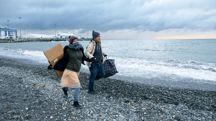 happy homeless couple, a man and a woman running on the beach