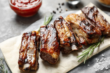 Delicious grilled ribs with rosemary on table, closeup