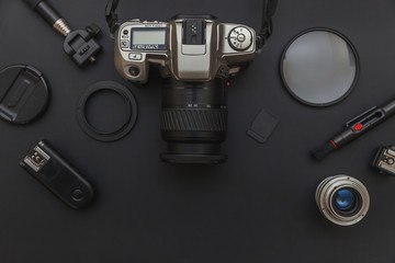 Photographer workplace with dslr camera system, camera cleaning kit, lens and camera accessory on dark black table background. Hobby travel photography concept. Flat lay top view copy space.