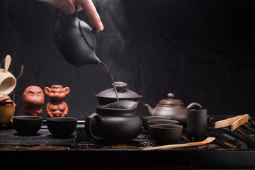 Pour hot water with a small Chinese teapot. Brewing green tea in China, tea, tableware, kettle,...