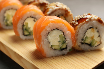 Delicious sushi rolls on wooden tray, closeup