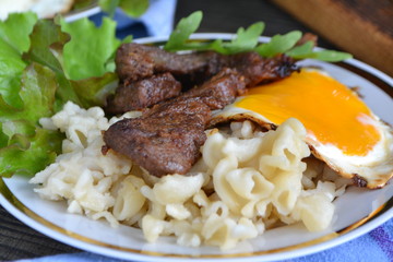 pasta with vegetables grilled meat and egg, russian cuisine, close up
