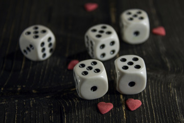dice on a black table with red hearts