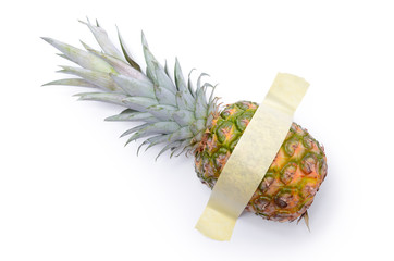 Pineapple glued with yellow tape to a white surface. Modern pop-art.