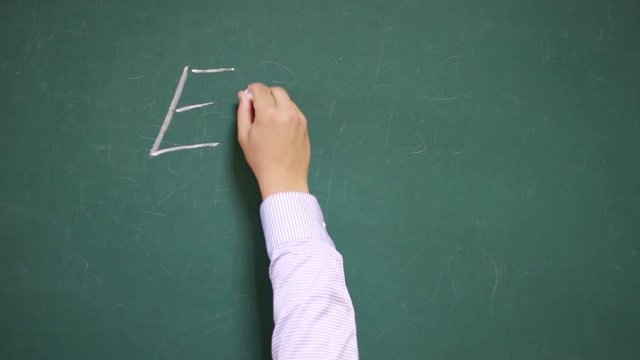 Hand writes Mass&ndash;energy equivalence formula (E=mc2) on a school blackboard