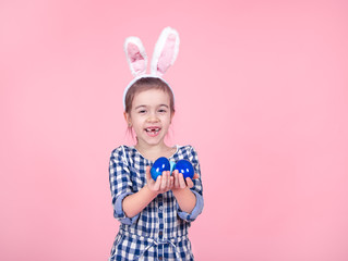 Portrait of a cute little girl with Easter eggs on a pink background.
