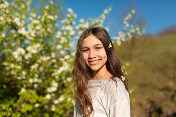 Portrait of a young beautiful teenager girl in a blooming spring green garden