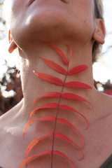 Red leaves of a plant against the background of a woman's body somatic motive.