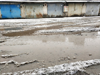 Winter dirty broken road in a garage cooperative. Gray depressing moody winter