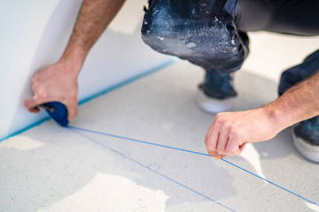 Handwerker markiert den Estrich mit einem Schnurschlag aus blauem Kreidepulver