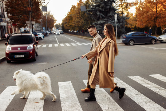Young funny couple with white dog on the street