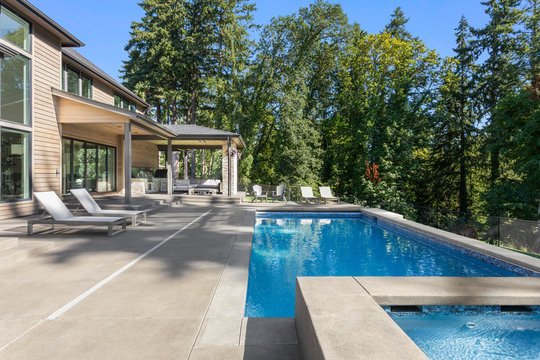 Luxury Home Exterior And Pool On Sunny Day With Blue Sky