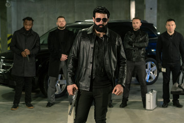 Bearded criminal authority in sunglasses, black leather jacket and jeans