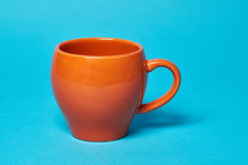 Orange cup isolated on a blue background. Free space for text