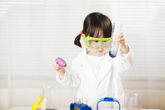 toddler girl pretend play  scientist  role  at home against white background