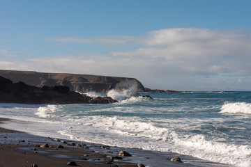 Waves splashing at the rocky ocean shore. Ajuy beach, Fuerteventura, Canary Islands. 
