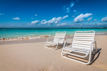 Twee witte strandstoelen op Seven Mile Beach in Grand Cayman, Cayman Islands.