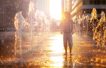 Child stand and play on street fountain on Philadelphia square over sunset near city hall in downtown