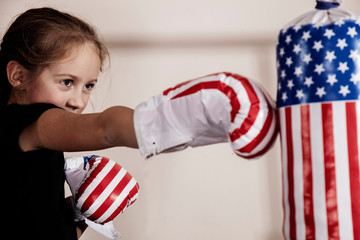 American boxing concept. Young child girl fighter with boxing gloves in flag of USA.