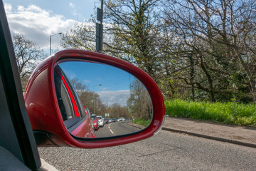 Heavy London traffic viewed in the reflection of a car wing mirror