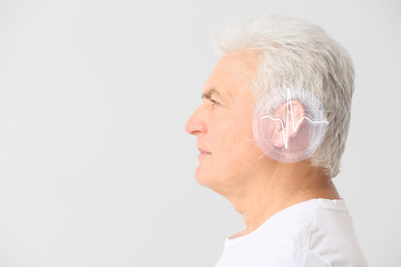 Handsome mature man with hearing problem on light background