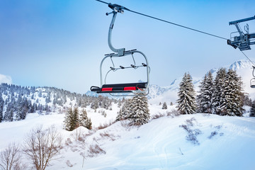 Ski lift chair on Alpine resort over fir and pine forest covered with snow after strong snowfall