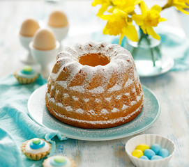 Easter yeast cake sprinkled with powdered sugar on a turquoise plate. Traditional Easter dessert in...