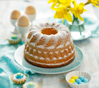 Easter yeast cake sprinkled with powdered sugar on a turquoise plate. Traditional Easter dessert in Poland