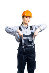 The construction girl in a helmet laughs and shows a gesture down. Isolated
