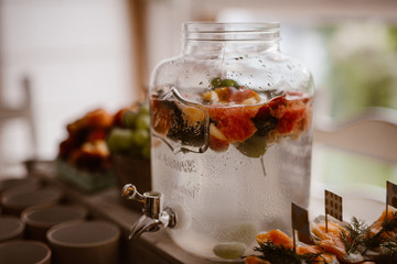 fruit infused flavored water, lemonade, cocktail in a beverage dispenser with fresh fruits