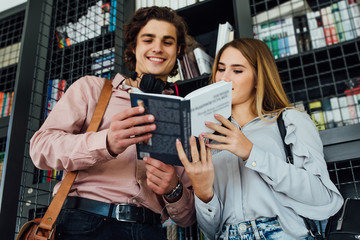 Portrait of young couple in library reading book.