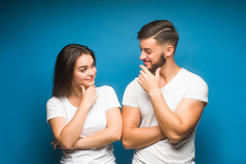 Pretty young couple gesturing isolated on blue background. Candid emotions.
