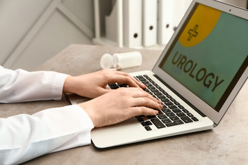 Female urologist working on laptop at table