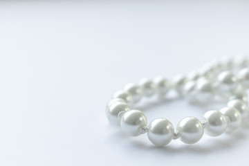 White pearls necklace on white background, clean and tidy picture, shiny pearl, close view and lots of negative space