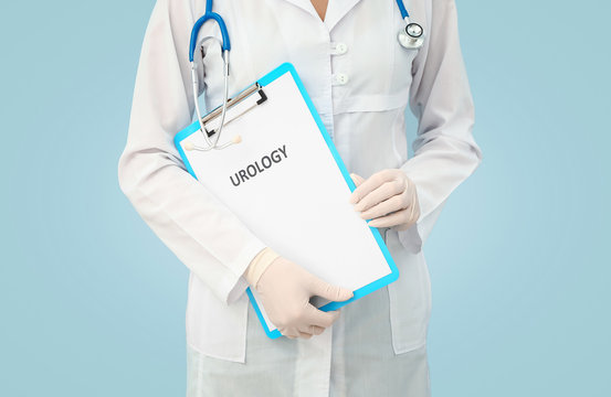 Female urologist with clipboard on color background, closeup