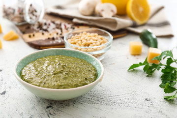 Bowl of tasty pesto sauce on white background