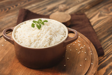 Pot with boiled rice on wooden table