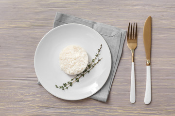 Plate with boiled rice on white wooden background