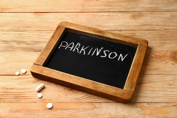 Chalkboard with text PARKINSON on wooden background