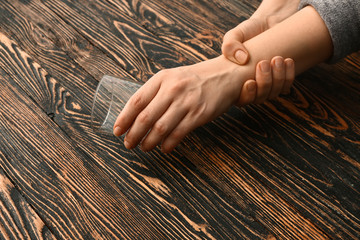 Woman suffering from Parkinson syndrome with empty glass at table, closeup