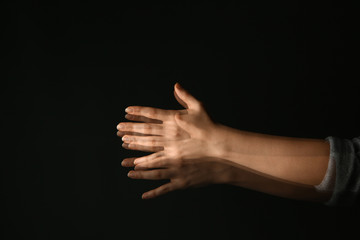 Hands of woman suffering from Parkinson syndrome on dark background