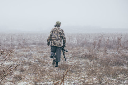 Soldier With Weapon Walking Away In Field