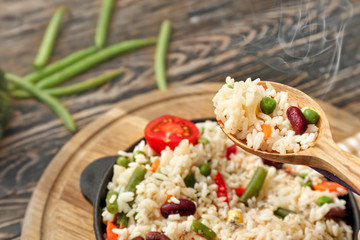 Spoon with hot boiled rice and vegetables, closeup
