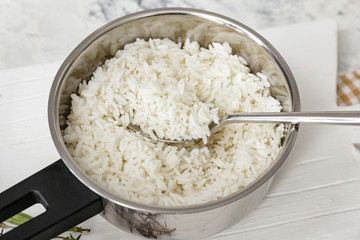 Saucepan with boiled rice on table, closeup