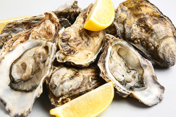 Tasty oysters with lemon on white background, closeup