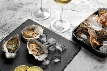 Slate plate with tasty cold oysters and wine on white background