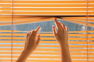 Woman opening blinds on window