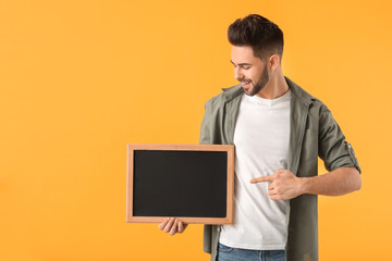 Young man with chalkboard on color background